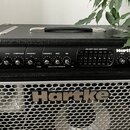 Černý basový kombozesilovač s kovovou mřížkou reproduktoru. Na horním ovládacím panelu je nápis 250 WATT BASS AMPLIFIER a logo Hartke. Panel obsahuje…
