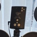 Černý ovládací modul elektronických bicích umístěný na stojanu. Na přední straně je viditelné logo Roland a několik ovládacích tlačítek. Povrch modul…