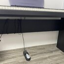 Digitální piano s klávesnicí v černém provedení, umístěné na černém stojanu. K pianu je připojena sustain pedál v černé barvě s bílým šlapadlem. Na f…