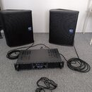 Dva černé reproduktory s mřížkami a modrými logy „dB Technologies“. Mezi nimi je umístěn černý rackový zesilovač s nápisem „skytec PRO244“ a „AMPLIFI…