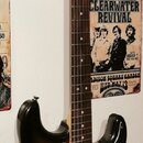 Elektrická kytara typu Stratocaster s korpusem v barevném přechodu od černé přes hnědou k žluté a s černým pickguardem. Na hlavě hmatníku je vidět ná…
