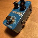 Modrý efekt pedál s nápisy FLASHBACK MINI a tc electronic. Na horní straně jsou tři černé oválné ovládací knoflíky a jeden stomečový spínač s nápisem…