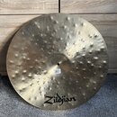 Kovový činel s matným povrchem a výrazným kovánívým vypracováním (důlky po kladivu). V dolní části je černé logo Zildjian. U středu činelu je viditel…