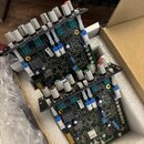 Dvě elektronické desky s řadou bílých a červených potenciometrů, umístěné v polystyrenovém obalu v kartónové krabici. Na deskách jsou viditelné různé…
