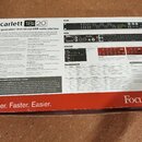 Fotografie zachycuje otevřenou kartonovou krabici s USB audio rozhraním Scarlett 18i20. Uvnitř je umístěno zařízení v šedé barvě s červenými detaily…