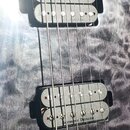 Detail elektrické kytary s šedým plamenovitým povrchem. Nástroj má dva černé humbuckery, z nichž na spodním je viditelný nápis Seymour Duncan. Povrch…