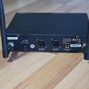 Černý bezdrátový přijímač s dvěma anténami. Na zadním panelu jsou nápisy 823-832MHz, 12V⎓/1000mA a označení výstupů BALANCED OUTPUT B, BALANCED OUTPU…