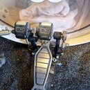 Krytý basový pedál značky Pearl s kovovým šlapadlem a černými plastovými komponenty. Na horních částech jsou viditelná loga Pearl a na spodní části š…