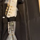 Bílá kytara zabalená v ochranné plastové fólii, umístěná v černém měkkém pouzdře. Na hmatníku je viditelné logo značky Chord. V horní části pouzdra j…