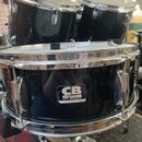 Tři černé bubny s chromovaným kováním. Na předním bubnu je viditelný nápis CB drums SP SERIES a menší text CHINA. Povrchy jsou glossy, s viditelnými…