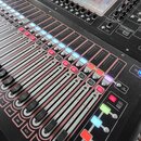 Černý digitální mixovací pult s displejem a mnoha posuvníky. V horní části je nápis DiGiCo S09. Na spodní části panelu je vidět logo SUPER. Povrch př…