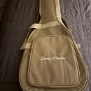 Béžový poloměký pouzdro (gig bag) na kytaru s ramenním popruhem. Na přední kapse je bílý nápis Harley Benton. Povrch materiálu vypadá čistě a bez vid…