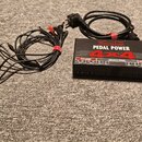 Černý napájecí adaptér Voodoo Lab PEDAL POWER 4x4 s nápisy HIGH CURRENT a ISOLATED DC OUTPUTS. K zařízení patří napájecí kabel do zásuvky a sada čern…