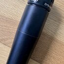 Černý dynamický mikrofon s mřížkou v horní části. Na kroužku pod mřížkou jsou bílé nápisy SM57 a DYNAM. Povrch těla vykazuje mírné známky opotřebení…