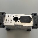 Zadní strana stříbrného kovového zařízení s černými plastovými úchyty po stranách. Na povrchu jsou nápisy CE, OUTPUT, 9V BATTERY a Made in PRC 23-001…