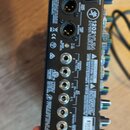 Zadní strana černého míchacího pultu s řadou konektorů. Na šasi je uveden model 1202VLZ4 a logo Mackie. Jsou zde viditelné nápisy MAIN OUTPUT, AUX SE…