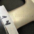 Detailní záběr na béžový kovový rám hudebního nástroje. Na povrchu je vyražen nečitelný kód, ze kterého jsou rozpoznatelná čísla 35/04. K rámu je při…