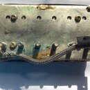 Detail kovové části nástroje, pravděpodobně mostu nebo základny snímače, s viditelnou korozí a oxidací povrchu. Uprostřed je vyražen nápis Gibson, kt…