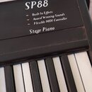 Detailní záběr na klávesy a horní část černého digitálního piana. Na černé ploše je bílým nápisem uveden model SP88 a označení Stage Piano. Pod tím j…