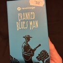 Modrá papírová krabice s nápisy a grafikou. V horní části je bílé logo blesku a text revoltage, pod ním žlutý nápis CRANKED BLUES MAN. Spodní část zd…