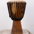 Djembe s dřevěným korpusem v přirozené hnědé barvě. Horní část je obvolta opletena černými provazy, které drží napnutou koženou membránu. Spodní část…