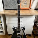 Černá elektrická kytara s bílým pickguardem a chromovaným hardwarem. Na hlavě hmatníku je bílý nápis GRETSCH. Tělo kytary má dva snímače a ovládací k…