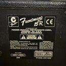 Fotografie zachycuje štítek s technickými údaji na zadní straně černého kytarového komba. Na štítku je logo Fender a nápis Frontman 15R, značka CE a…