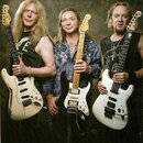 Tři muži držící elektrické kytary typu Stratocaster. Nejvlevo je bílá kytara s viditelným opotřebením laku na těle, vprostřed černá kytara s bílým pi…