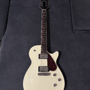 Bílá elektrická kytara s tvarem připomínajícím Les Paul a tmavým hmatníkem. Na hlavě je nápis KRAETEN. Nástroj má dva humbuckery, tmavě červený plech…