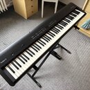 Černý digitální klavír značky Roland, model FP-50. Nástroj je umístěn na černém kovovém stojanu. Povrch klavíru vypadá čistě a bez viditelných poškoz…