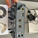 Zadní strana šedého elektronického zařízení s nápisem E-MU. Jsou zde vidět konektory USB, 5 VDC, MIDI Out a MIDI In, stereo výstupy Outputs L a R a v…
