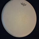 Bílá kruhová bubenová blana. V horní části je černé logo REMO s korunkou a pod ním nápisy EMPEROR®, COATED a MADE IN U.S.A. Povrch blány vykazuje v c…