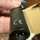 Detailní pohled na konec černého plastového kabelu s trojpólovým konektorem. Na povrchu je viditelné šedé označení CE. Povrch plastu je matní a bez v…