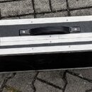 Černý obdélníkový tvrdý kufýr s hliníkovými hranami a rohy. Má čtyři kovové zapínací zámky a uprostřed černou plastovou rukojeť. Povrch je potahen te…
