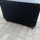 Černý obdélníkový reproduktorový box s povrchem z textilie. Na zadní straně je umístěn jeden konektor pro kabel a v horní části horního panelu je výř…