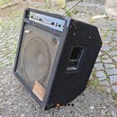 Černý basový kombo zesilovač s látkovým potahem a kovovou mřížkou reproduktoru. Na horním ovládacím panelu je nápis MICRO-BASS AMP a několik regulačn…
