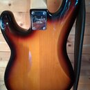 Zadní strana elektrické kytary s lakem v přechodu od černé k žluté (sunburst). Na kovovédesce krku je viditelné logo Fender a nápis STRATOCASTER CALI…