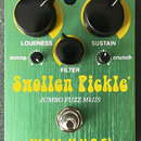 Zelený kytarový efekt s nápisy Swollen Pickle a JUMBO FUZZ MkIIS. Dole je žluté logo WAY HUGE BY GEORGE TRIPPS. Na horní straně jsou tři černé otočné…