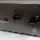 Šedý kovový box s nápisem Power ATTENUATOR a logem HB. Na předním panelu jsou dva černé oválné ovladače s popisky Line Level a SPK Level, oba mají st…