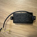 Černý humbucker s plastovým krytem a dvěma řadami šesti polkovníků. Na povrchu je vyražen nápis MIGHTY MITE MOT BUCKER. Z nástroje vedou dva elektric…
