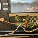 Fotografie zachicuje vnitřek elektronického zařízení s viditelnými zapojenými deskami plošných spojů a kabeláží. Na levé malé desce je nápis ENC2028…