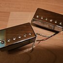 Dva elektrické kytarové snímače typu humbucker s chromovaným kovovým krytem. Oba mají na horní straně pět viditelných pólů. Z jednoho ze snímačů vedo…