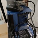 Modrý kovový počítačový case s černou myší položenou na hornídesce. Na spodní části je vidět krabice s nápisem „U“, „24-CHANNEL DIGITAL MIXER WITH WI…