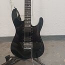 Černá elektrická kytara s dvojcutem, umístěná na černém stojanu. Nástroj má dva humbuckery a jeden snímač typu single-coil, chromovaný kobylník s pák…