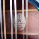 Fotografie zachycuje vnitřek akustické kytary s viditelnou štítkovou nálepkou na desce. Na štítku je nápis ELUXE EDITION, logo ve tvaru stylizovaného…