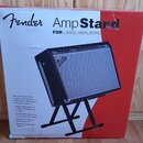Krabice s produktem, na které je nápis Fender Amp Stand FOR LARGE AMPLIFIERS. Na obrázku je zobrazen černý kytarový kombozesilovač s logem Fender umí…
