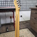 Zadní strana krku a hlavy světle hnědé elektrické kytary z dřeva. Na zadní straně hlavy je černý nápis ST22020002 a pod ním MADE IN JAPAN. Kytara má…