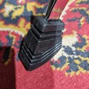 Detail černé gumové zátěrky na spodní části chromovaného kovového stojanu. Zátěrka má stupňovitý tvar s několika vrstvami. Na fotografii nejsou žádné…