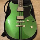 Zelená elektrická kytara s kovovými stupnicemi a dvěma humbuckery, umístěná v černém obalu. Tělo má metallic povrch s dvěma svislými černými pruhy a…