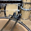 Detailní záběr na kovový mechanismus snareho (strunového mechanismu) u bubnu. Mechanismus je chromovaný a v napětí drží kovová struna přitisknutá k d…